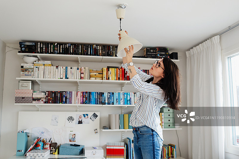 女人在家里更换灯泡图片素材