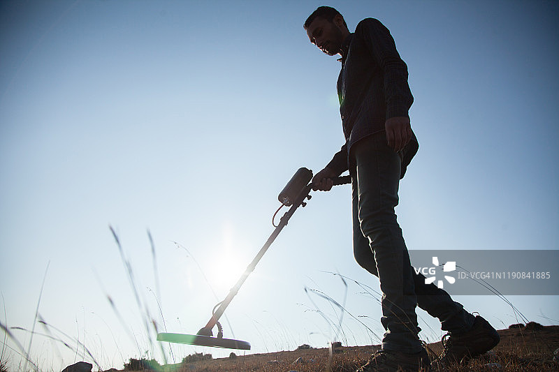 年轻人用金属探测器寻宝图片素材