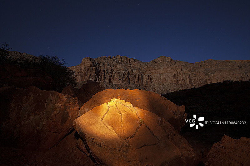 夜晚手电筒的橙色光芒照亮了龟裂的岩石图片素材