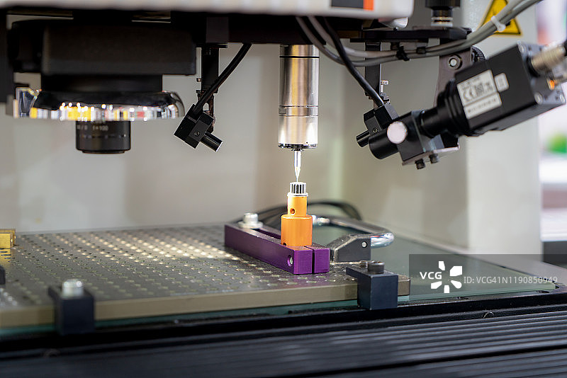 操作员用三轴测量机检测金属零件尺寸图片素材