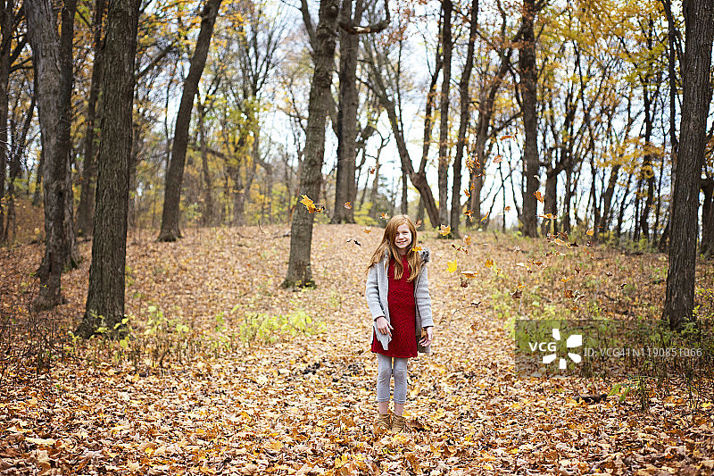 在秋叶中玩耍的年轻红发女孩图片素材