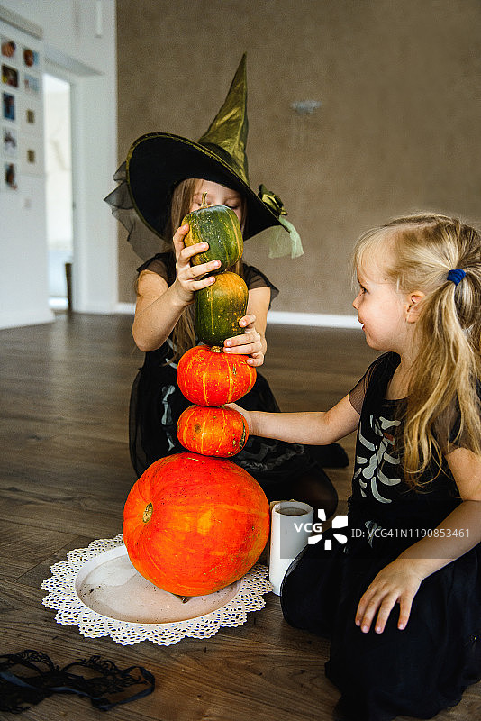 两个姐妹穿着万圣节骷髅服装，拿着南瓜图片素材