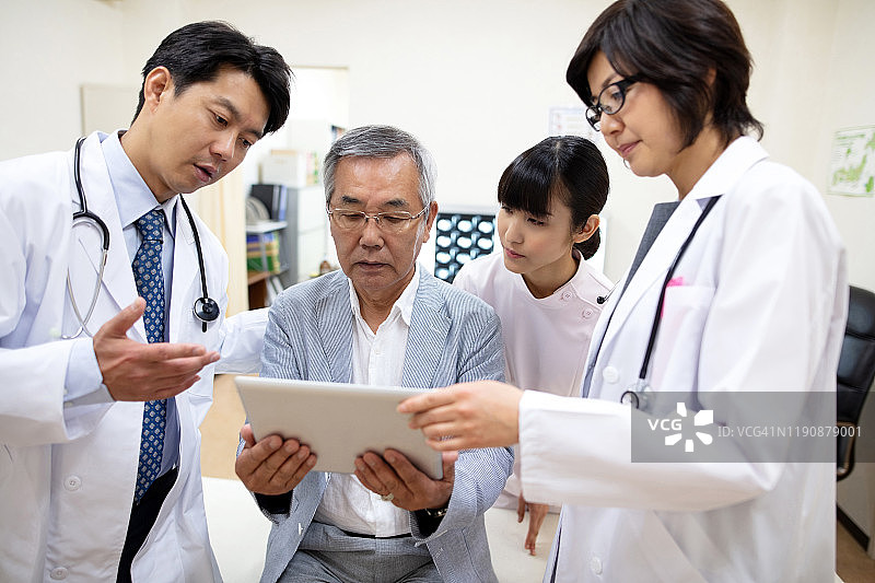 男女医生在医院通过电子病历向老年男性解释病情图片素材