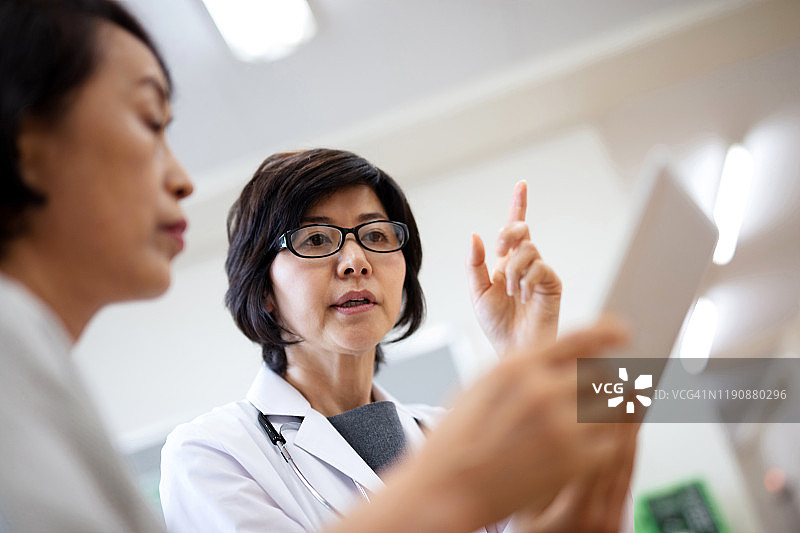 女医生在医院向老年患者讲解电子病历图片素材