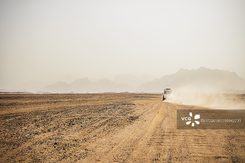 越野车在埃及苏伊士的干旱地形上行驶，背景是晴朗的天空图片素材