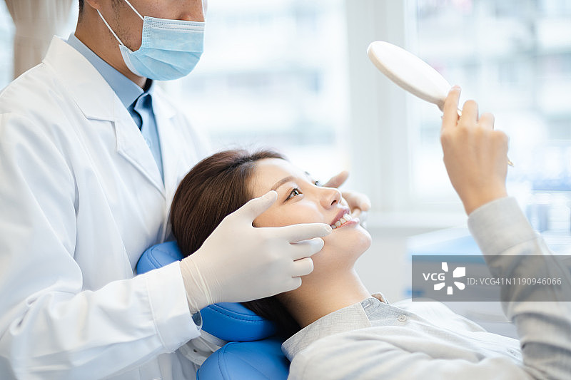 牙医在镜子里向患者展示她的新笑容图片素材