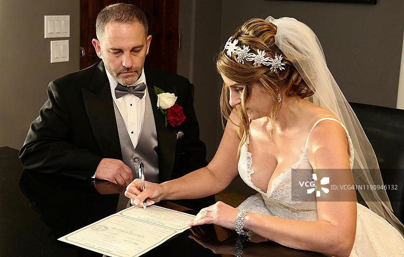 新娘签署结婚证书，新郎在一旁观看图片素材