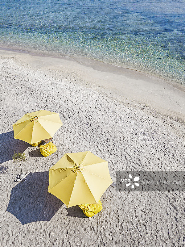 晴朗天气下，印度尼西亚吉利艾尔岛海滩上的黄色遮阳伞航拍图片素材