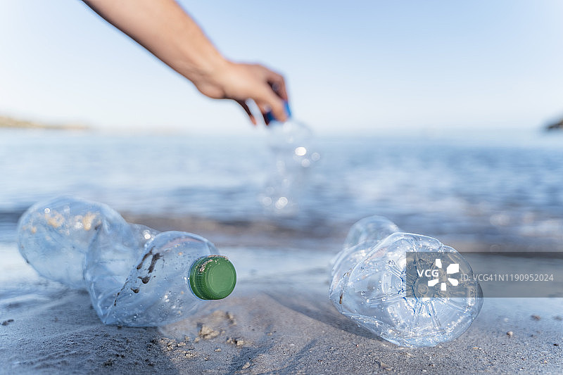 在海边捡拾空塑料瓶的手图片素材