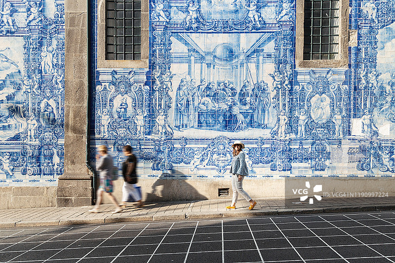 女士在波尔图灵魂教堂的瓷砖墙前散步图片素材