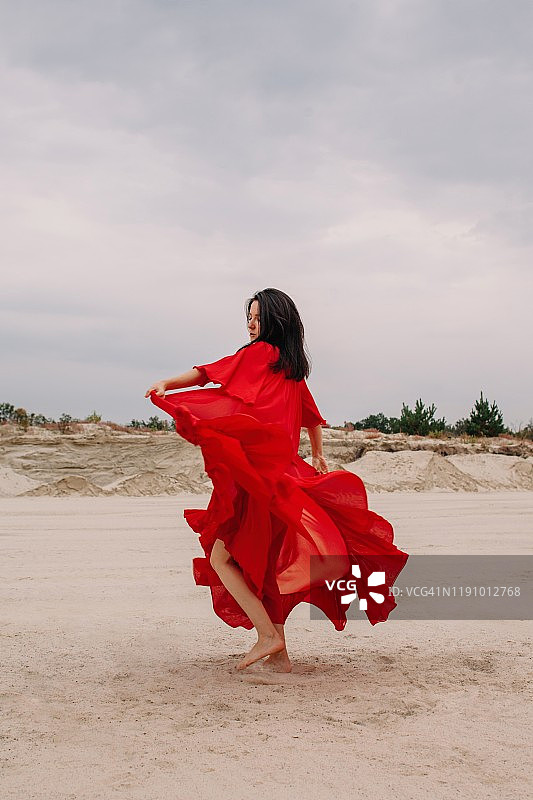 在俄罗斯沙漠中跳舞的红裙女人图片素材