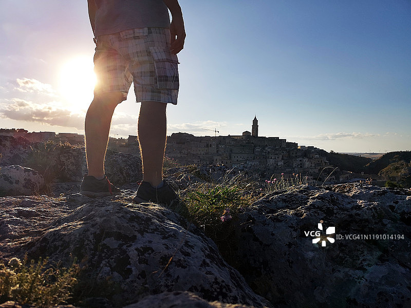 日落时分站在意大利马泰拉岩石上的男人图片素材