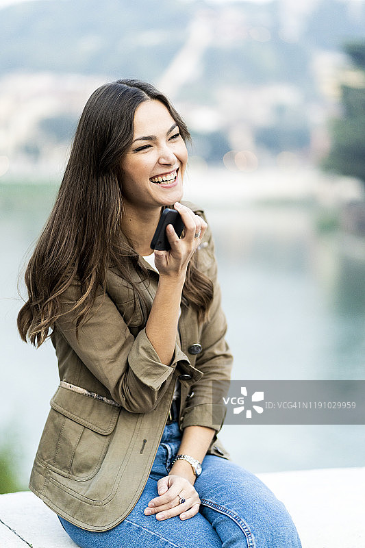 年轻的黑发女子在意大利维罗纳使用智能手机欢笑图片素材