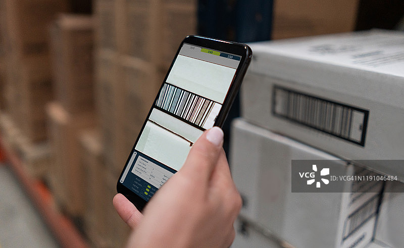 在仓库中使用手机扫描产品的女人图片素材