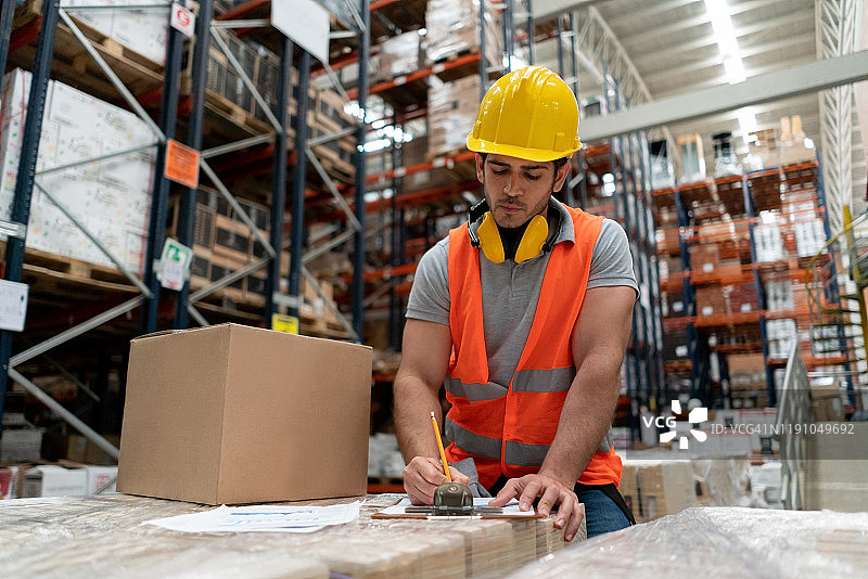 男子在仓库整理待运包裹图片素材