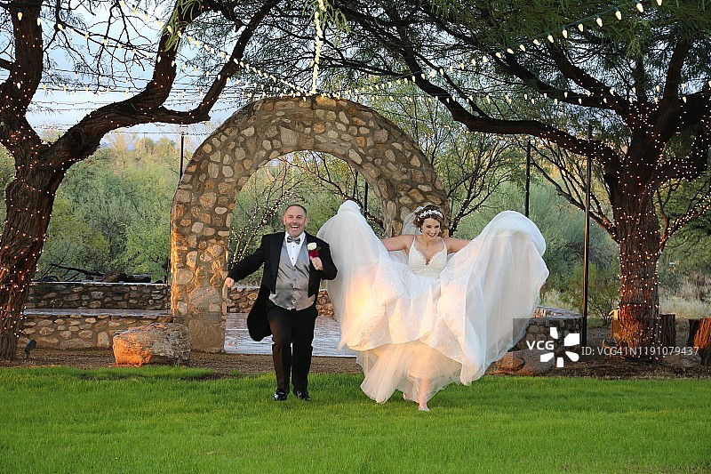 奔跑中的新娘和新郎，新娘撩起大婚纱图片素材