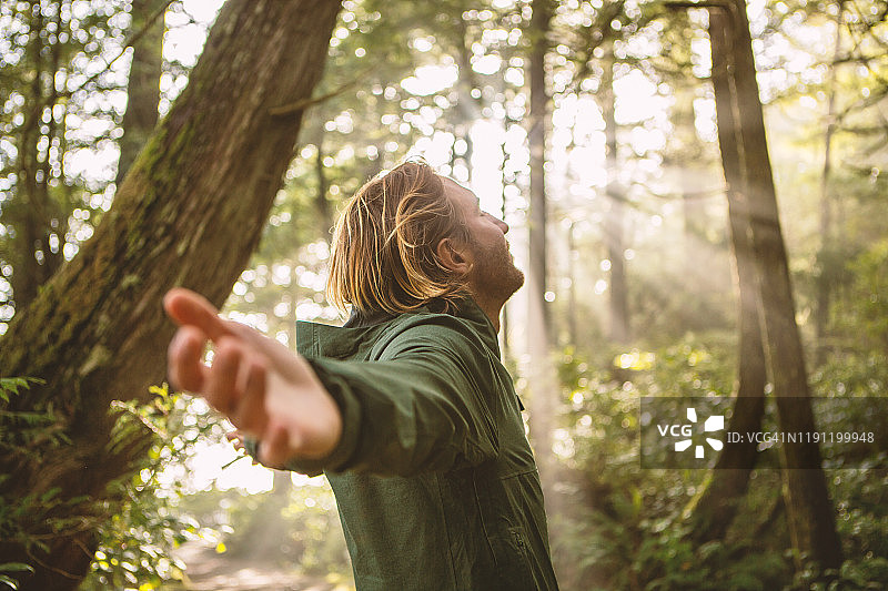 年轻男人在阳光照耀的雨林中拥抱图片素材