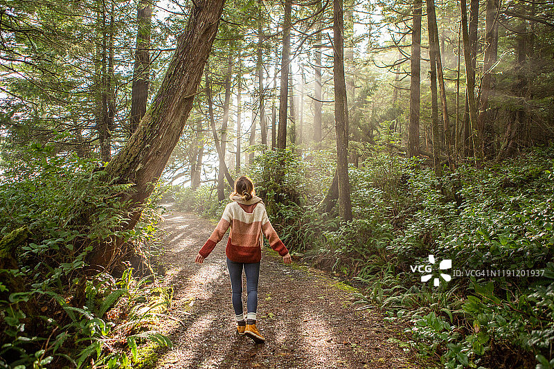 年轻女子沉思着照亮树木的雨林和阳光图片素材