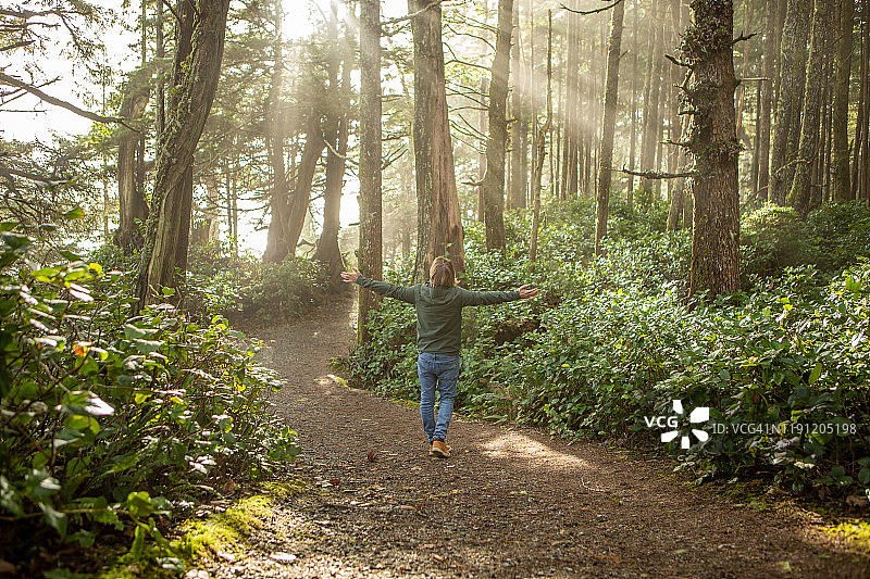 年轻男人在阳光照耀的雨林中拥抱图片素材