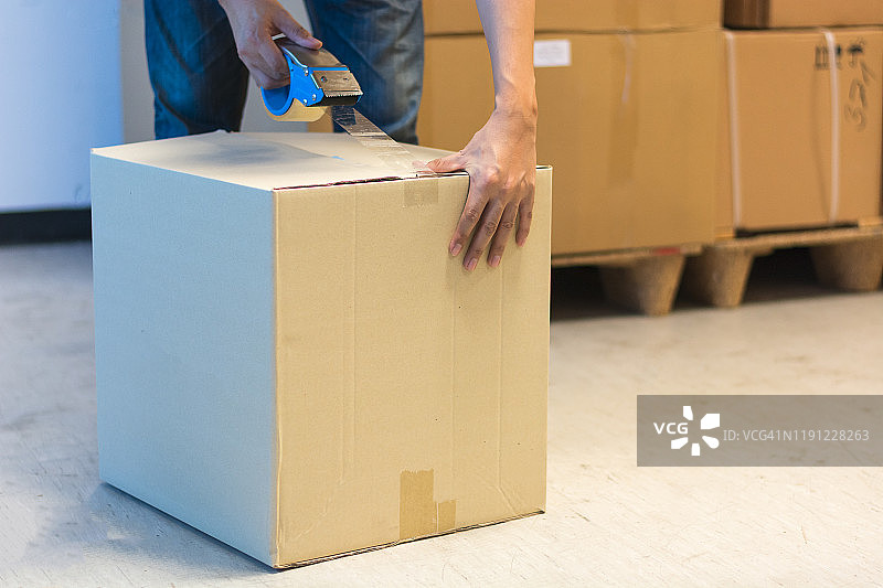 男子在仓库用胶带打包包裹特写图片素材