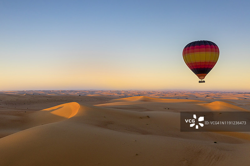 日出时分沙漠上空的彩色热气球图片素材