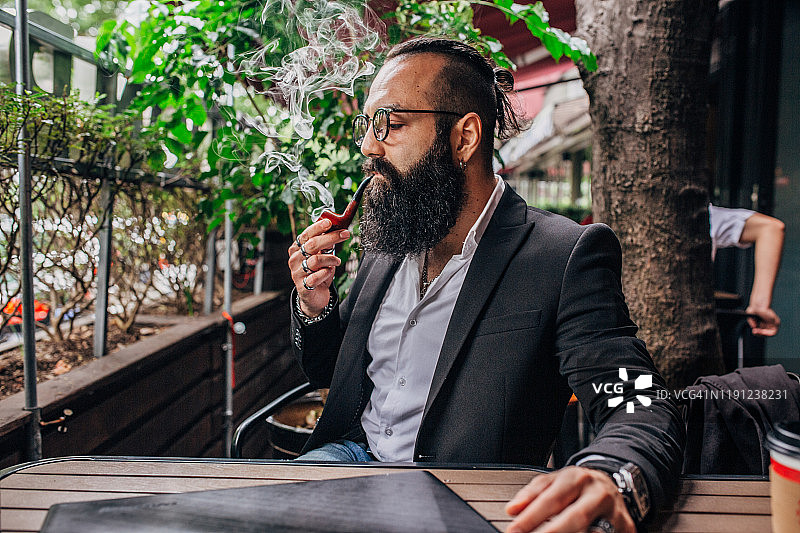 优雅的年轻商人抽着烟斗图片素材
