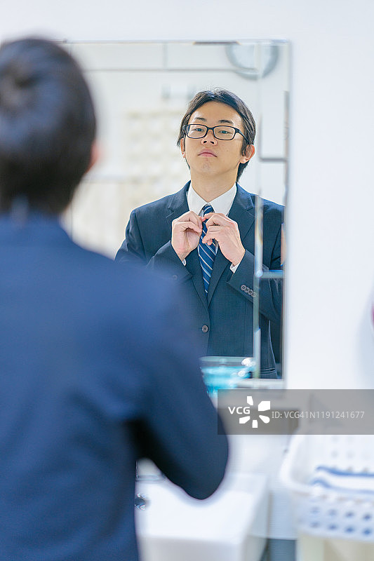 年轻商人对着镜子整理仪容图片素材