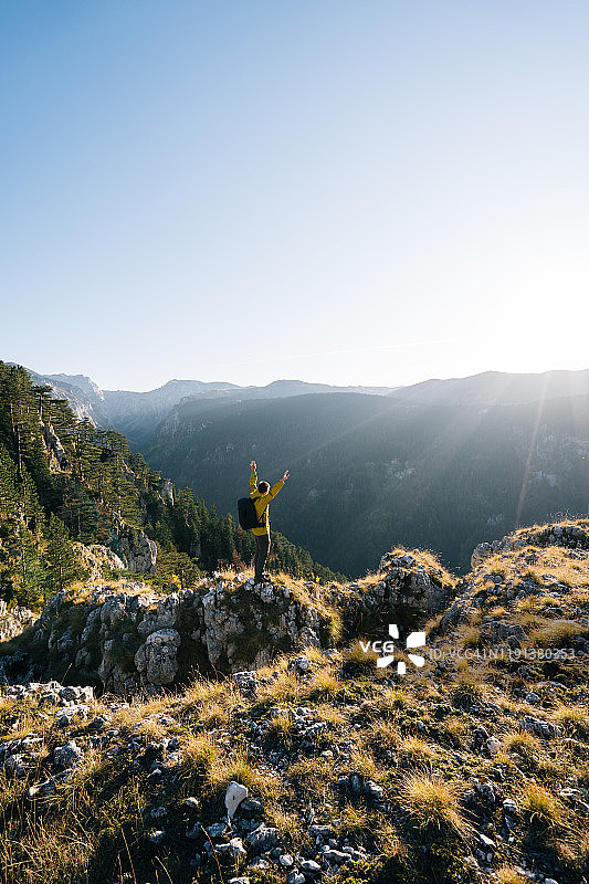 徒步旅行者在日出时于山谷上方放松身心图片素材