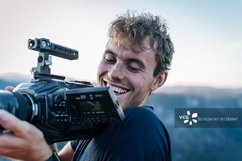 年轻男人在山脊上用摄像机拍摄图片素材