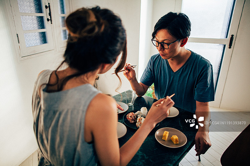 年轻情侣用筷子分享日式料理图片素材