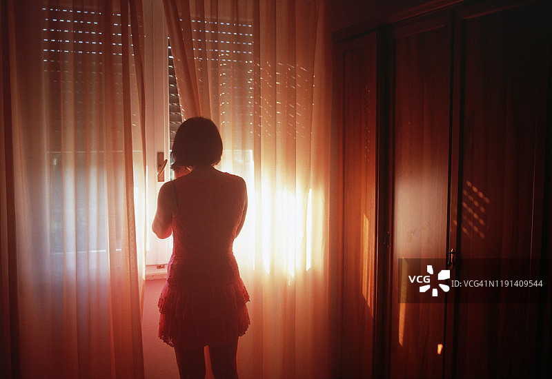 女子站在窗边，窗帘光线优美图片素材