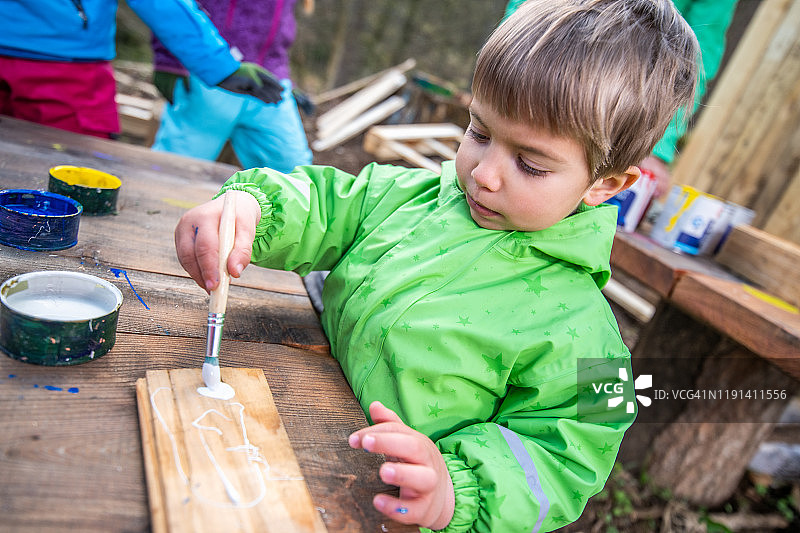 男孩在一块木头上绘画图片素材