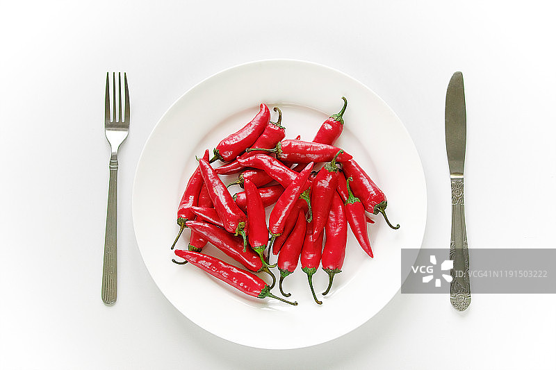 白盘上的火红卡宴辣椒，搭配刀叉，营养食品健康生活理念图片素材