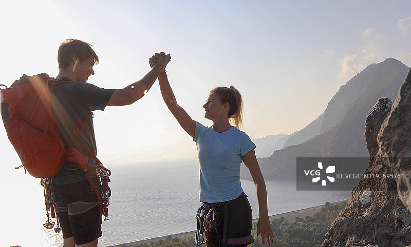 登山者日出时徒步登上岩石山顶图片素材
