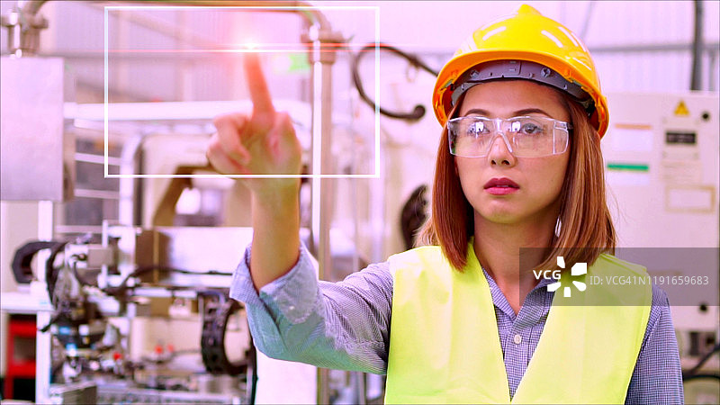 亚洲工程师戴黄色安全帽在工厂使用平板电脑控制机器，表情严肃图片素材