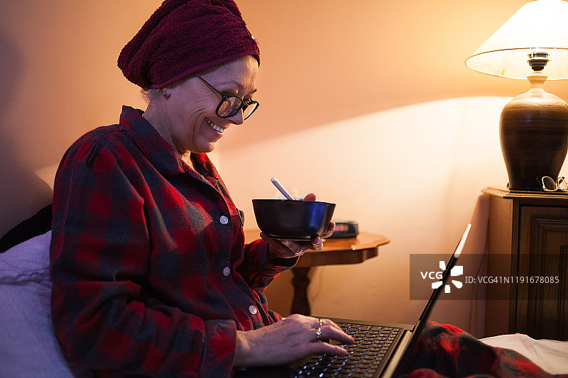 在床上使用笔记本电脑的老年妇女图片素材