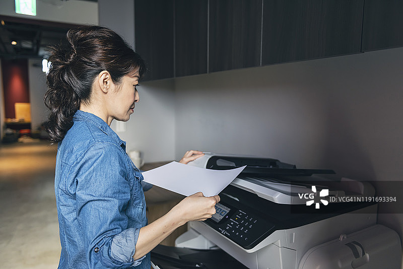 在办公室角落使用复印机的女人图片素材