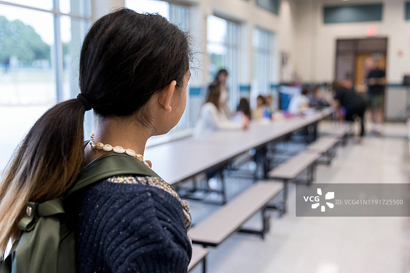独自站在学校食堂看着朋友们吃饭的年轻女孩图片素材
