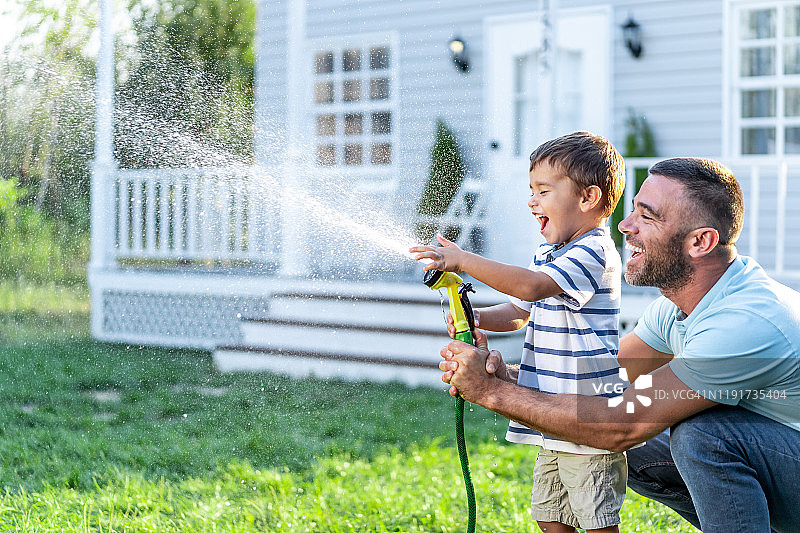 父亲在后院泼水，和儿子玩耍图片素材