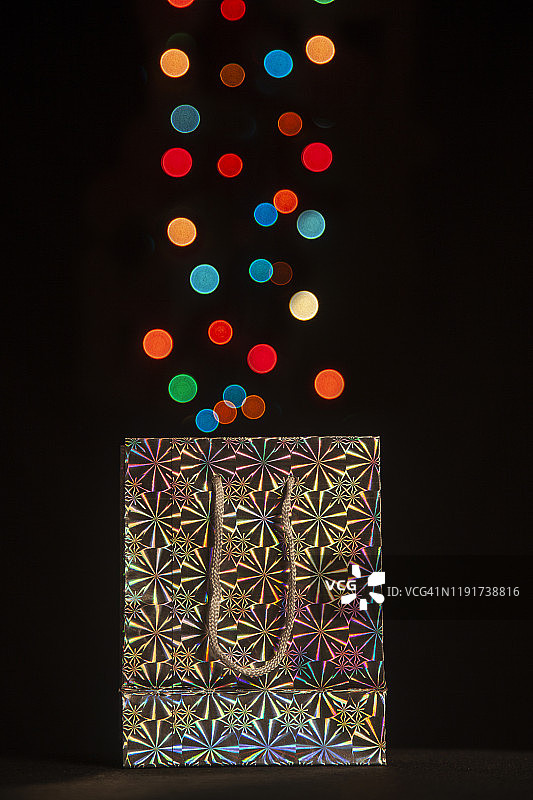 打开的礼品袋，从中散发出彩色灯光图片素材