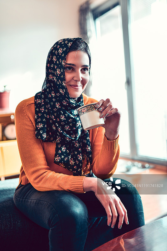 戴着头巾享受下午咖啡的女性图片素材
