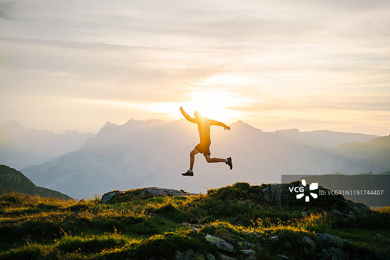 日出时在山脊上奔跑的年轻人图片素材