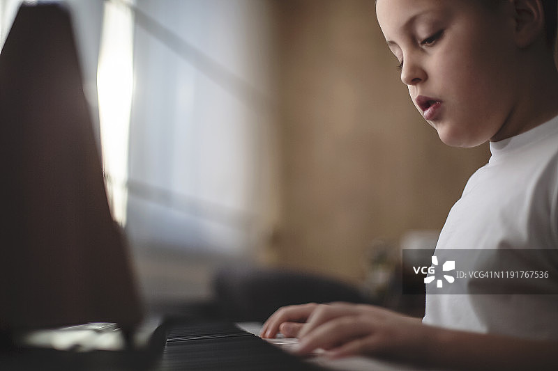 男孩在他的房间里弹钢琴图片素材