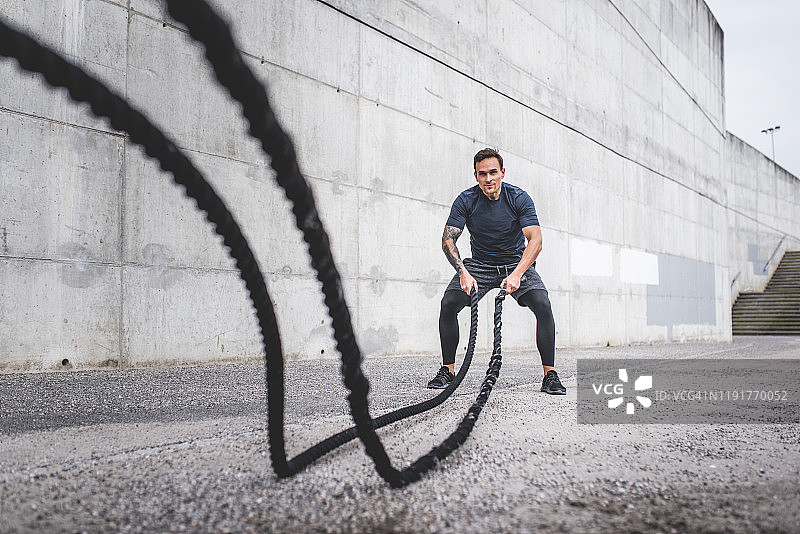 使用战绳在户外锻炼的白人男性运动员图片素材