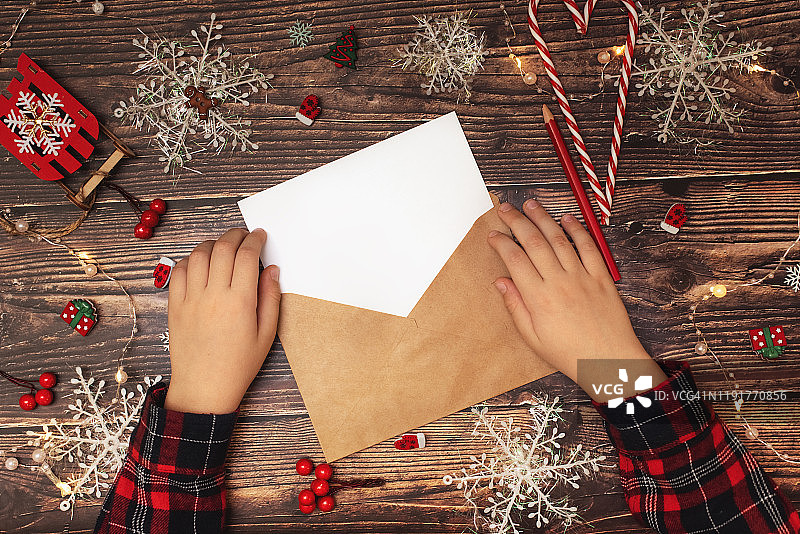 孩子给圣诞老人写信，木桌上有纸、铅笔和圣诞装饰，新年和圣诞节的概念，俯视图图片素材