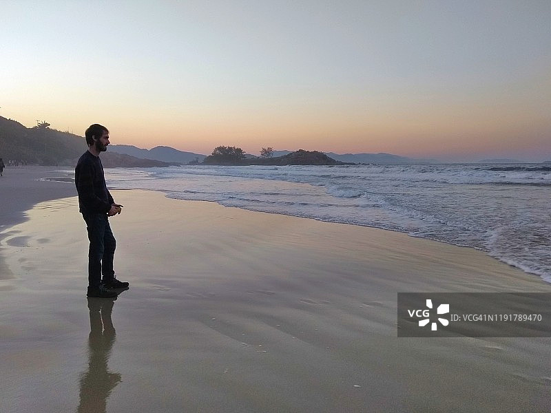 男子在巴西弗洛里亚诺波利斯马塔德罗海滩的波浪旁图片素材