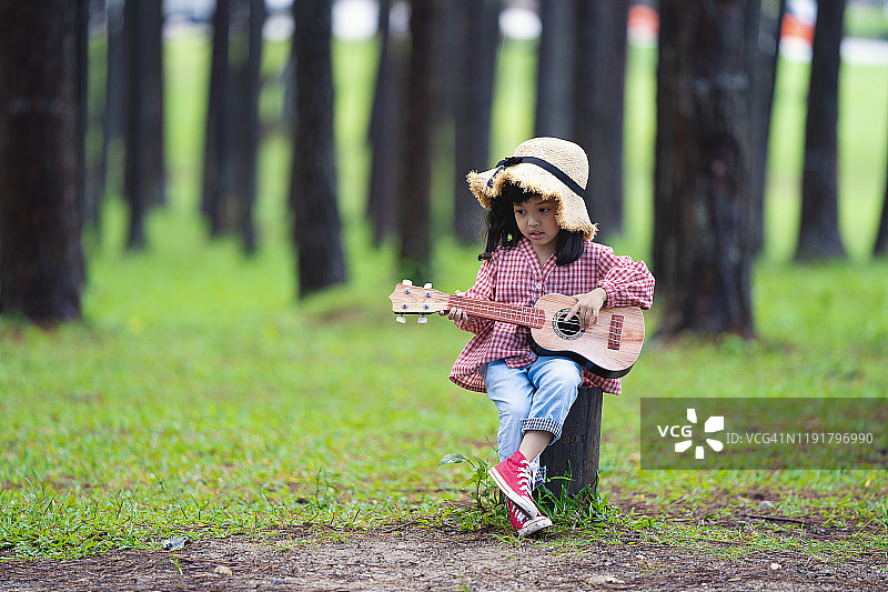 快乐的亚洲可爱小女孩弹吉他图片素材