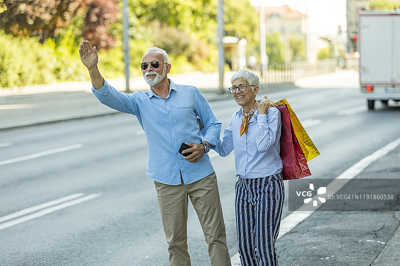 提着购物袋招手的年长夫妇图片素材