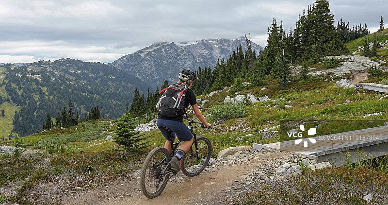 沿着山区高山小径骑山地自行车的年轻女人图片素材