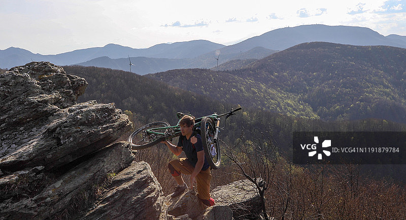 山地自行车骑行者扛车登上陡峭山脊图片素材